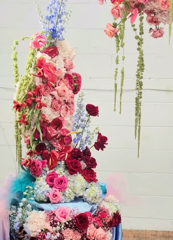 Red and pink ceremony pillar installation with hanging amaranthus