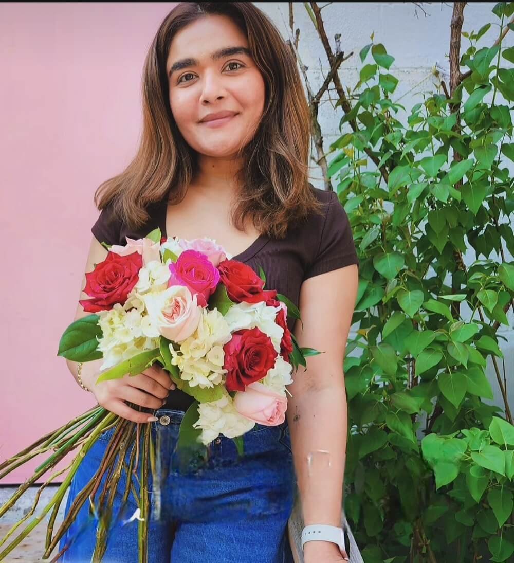 Student holding a hand-tied spiral bouquet of roses and hydrangeas